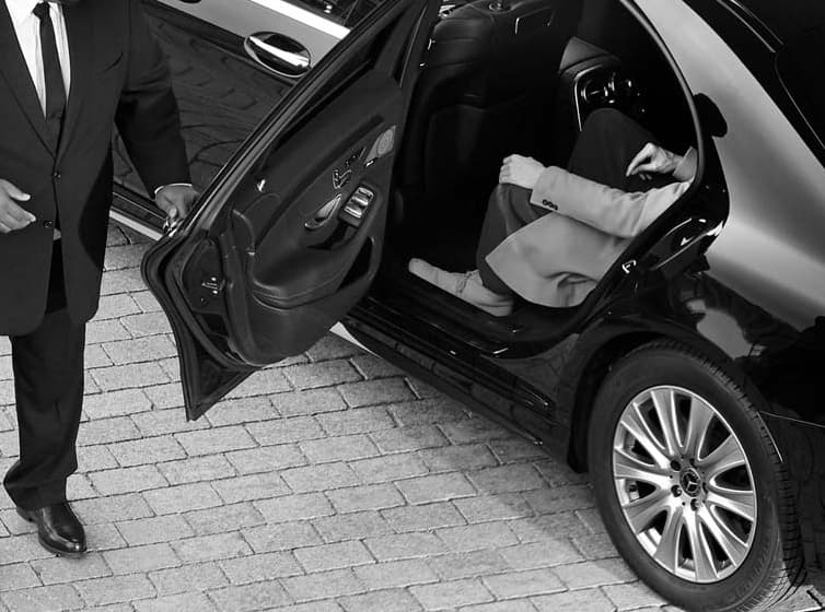Chauffeur assisting a passenger with luggage at an airport terminal